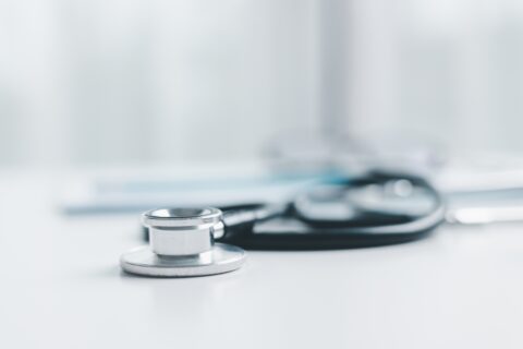 Stéthoscope posé sur un bureau médical blanc, symbolisant la consultation et le suivi de santé.