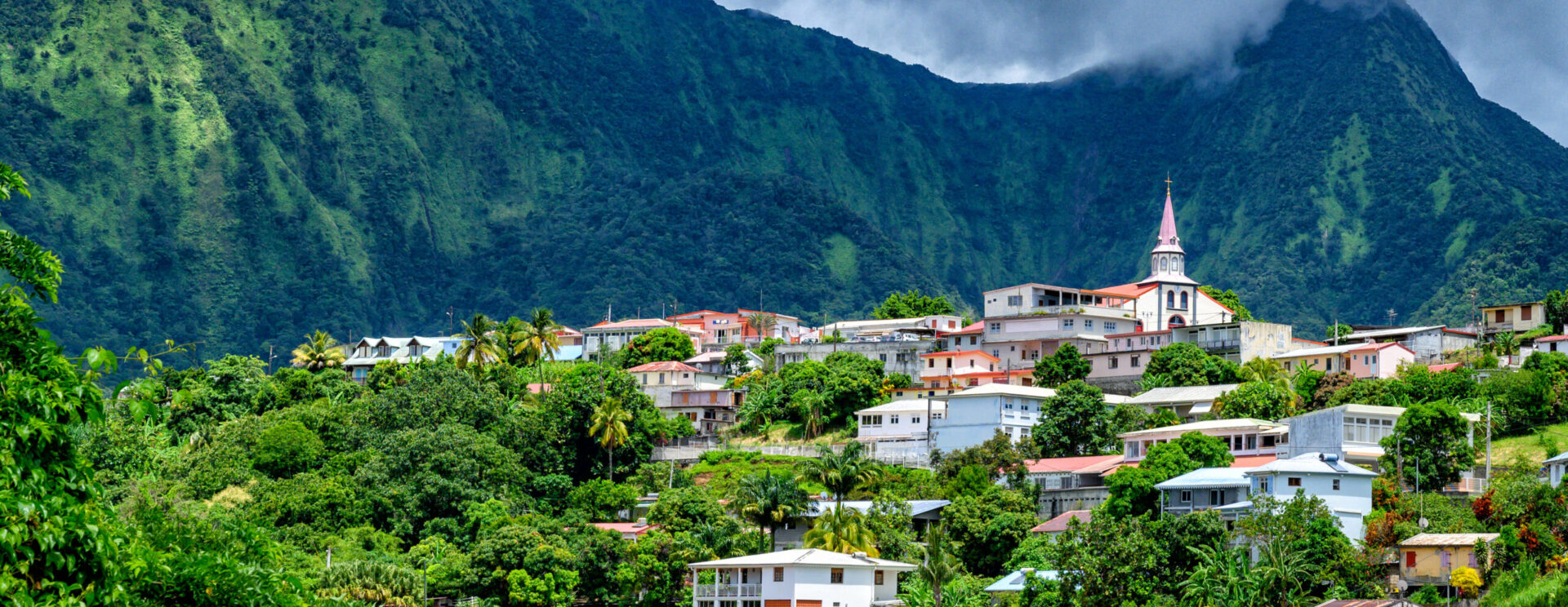 Vue d’un bourg antillais coloré niché au pied d’une montagne verdoyante