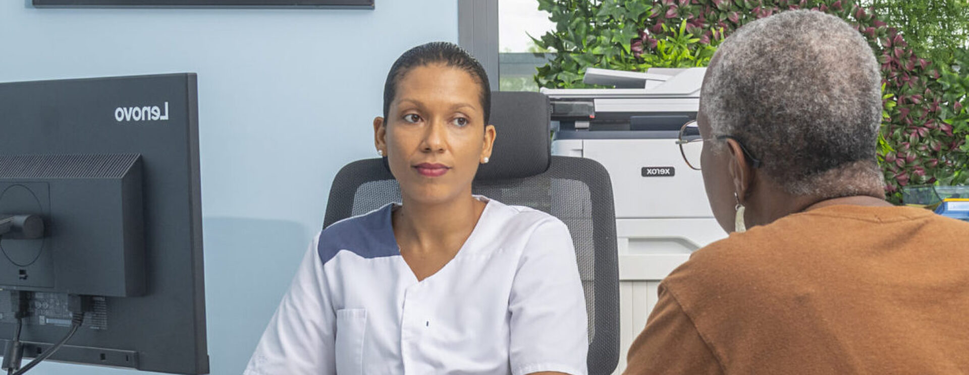 Consultation médicale entre une professionnelle de santé et une patiente dans un cabinet lumineux et moderne.
