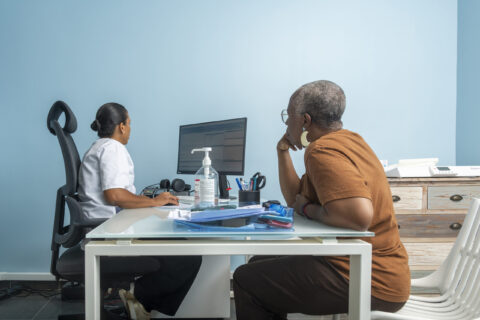 Consultation médicale entre une professionnelle de santé et une patiente dans un cabinet lumineux et moderne.